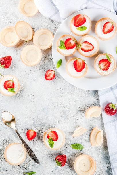 Καλοκαιρινό γλυκό σπιτικό επιδόρπιο, μίνι cheesecakes με φράουλα σε γκρι πέτρινο τραπέζι αντιγράψετε κάτοψη χώρου - Φωτογραφία, εικόνα