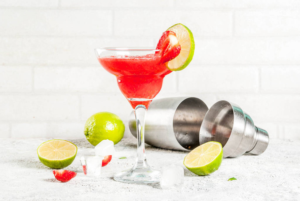 Cocktail de margarita aux fraises froides avec glace, citron vert et baies fraîches en verre de margarita, espace de copie de fond gris clair
  - Photo, image