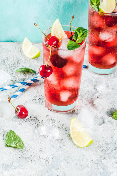 Bebida refrescante gelada de verão, limonada de cola de cereja ou coquetel de mojito em vidro alto, no espaço de cópia de fundo azul e cinza claro
 - Foto, Imagem