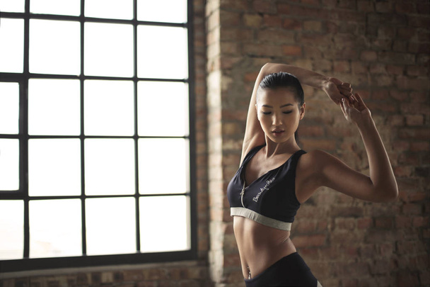 Young beautiful Asian woman stretching in the gym. - Фото, изображение