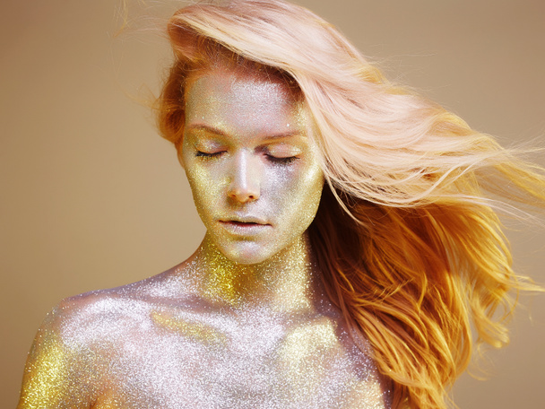 Mulher bonita em faíscas. Garota de ouro com arte make-up em luz de cor. voando modelo de cabelo saudável com maquiagem colorida
 - Foto, Imagem