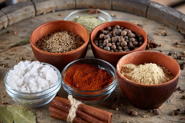 Spices in ceramic bowls on the top of wooden barrel, close-up, selective focus, vertical. - Фото, изображение