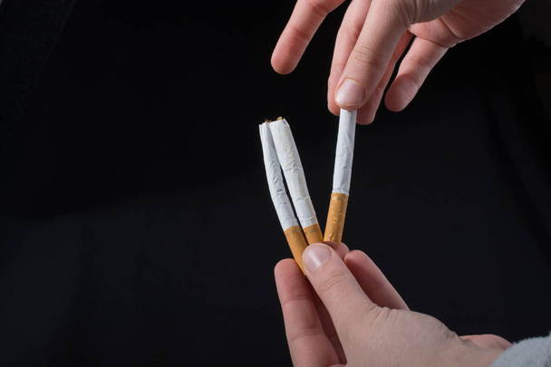 Рука видає сигарету на чорному тлі
 - Фото, зображення