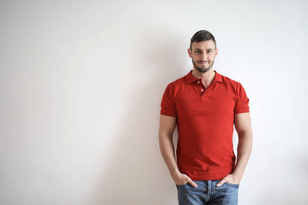 Young man in red t-shirt in front of a white wall indoor. - Fotografie, Obrázek