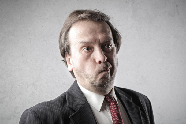 Businessman makes a face and thinks. - 写真・画像