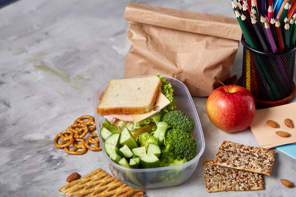 School or picnic lunch box with sandwich and various colorful vegetables and fruits on wooden background, close up. - Foto, Bild