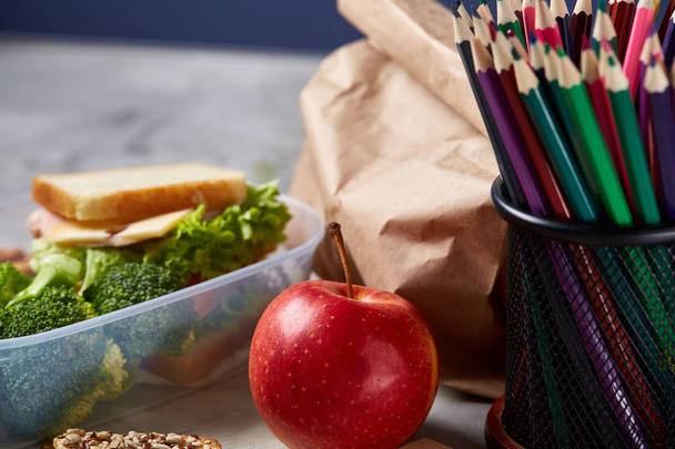 School or picnic lunch box with sandwich and various colorful vegetables and fruits on wooden background, close up. - Photo, image