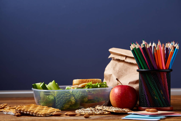 Concept of school lunch break with healthy lunch box and school supplies on white desk, selective focus. - Φωτογραφία, εικόνα