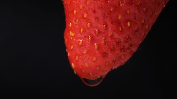 Wassertropfen fließen eine Erdbeere in Großaufnahme auf schwarzem Hintergrund herunter, Zeitlupe - Filmmaterial, Video