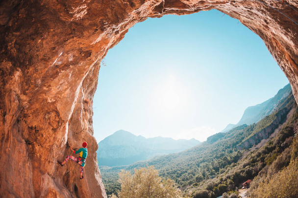 A woman climbs the rock. Rock in the form of an arch. Cave. Extreme sports. The athlete trains on a natural relief. The athlete overcomes a difficult climbing route. Rock climbing in Turkey. - Photo, Image