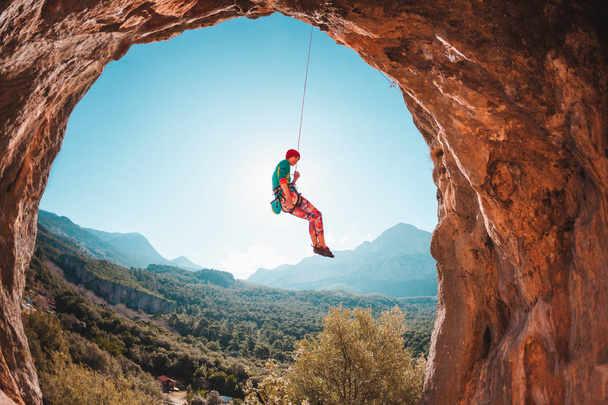 Der Kletterer hängt an einem Seil. geht das Mädchen unter. Klettern in der Türkei. Berglandschaft. Eine Frau treibt Extremsport. Felsen in Form eines Bogens. Kletterroute in der Höhle. - Foto, Bild