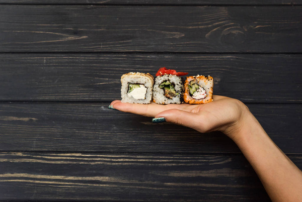 Sushi imbir na rękę dziewczyny na czarnym tle drewnianych - Zdjęcie, obraz