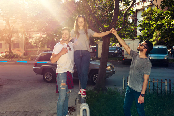 Gruppo di amici che camminano lungo la strada e si divertono nella giornata di sole
 - Foto, immagini