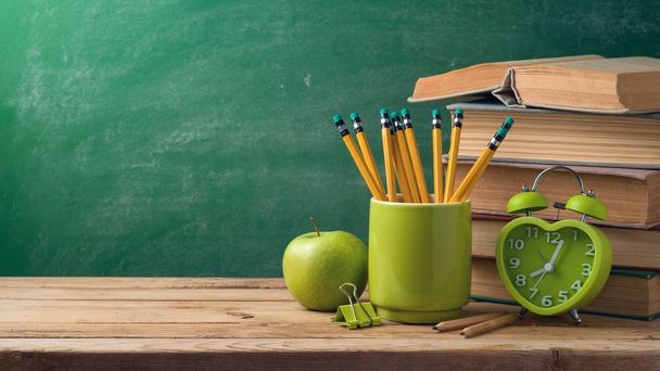 Back to school concept with pencils, alarm clock, apple and old books on table background - Photo, Image