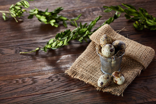 Rustic still life with quail eggs in bucket, box and bowl on a linen napkin over wooden background, selective focus - Foto, immagini