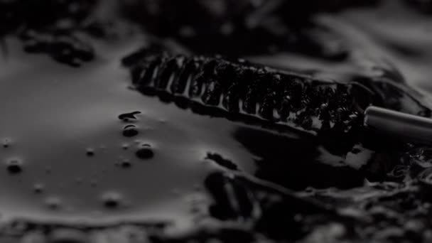 schwarze flüssige Textur und Mascara-Pinsel, der diese Flüssigkeit bewegt - Filmmaterial, Video
