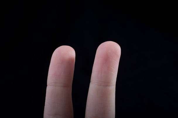 Два пальці руки дитини частково видно на чорному тлі
 - Фото, зображення