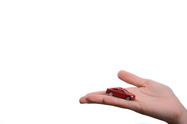 Die Hand des Kindes hält ein rotes Auto auf weißem Hintergrund - Foto, Bild