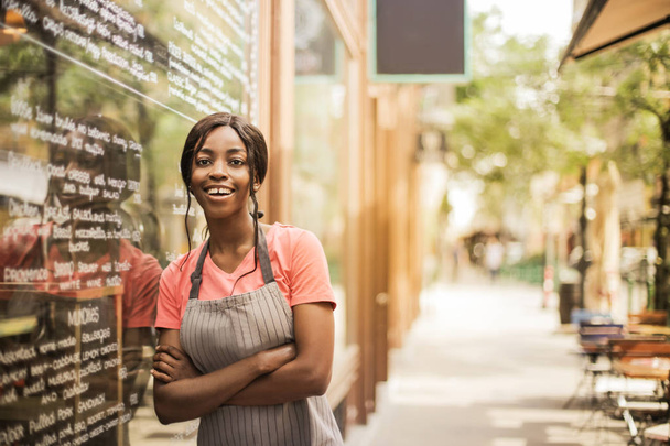 Молодий красива жінка афро офіціантка перед будівлі мають перерву і посміхається. - Фото, зображення