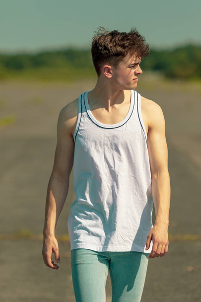 Young adult male walking outside in the sunshine - Valokuva, kuva