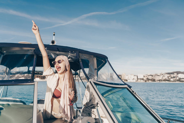 the joyful laughing girl enjoys a rich life on her yacht, sails the Caribbean sea and drinks champagne - Fotoğraf, Görsel
