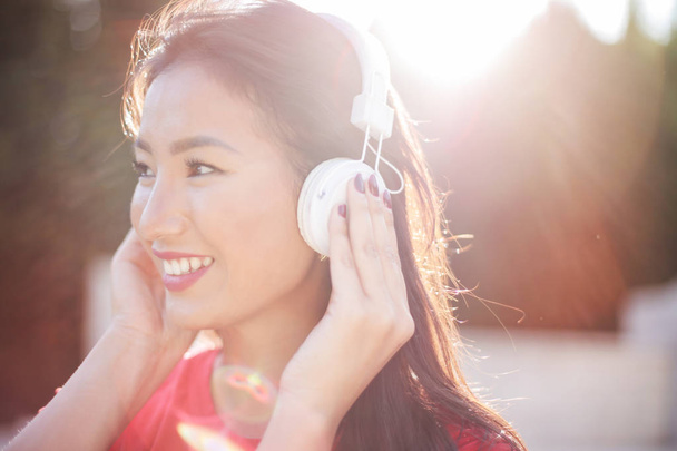 Beautiful Asian woman with earphones enjoying music and smiling. - Foto, Imagen