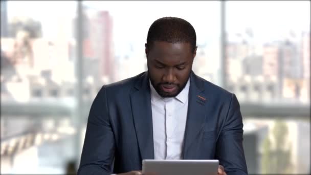 Mladý pohledný podnikatel hraje na pc tabletu. Afro-American chlap v formální oblečení pomocí digitálních tabletu na rozostřeného pozadí. - Záběry, video
