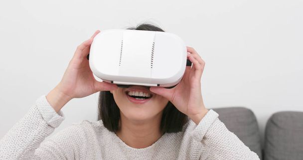 Donna che guarda con dispositivo VR a casa
 - Foto, immagini