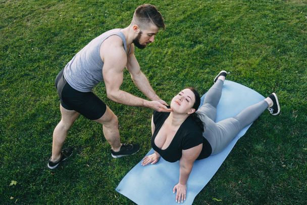 Obese woman doing yoga with personal trainer - Valokuva, kuva