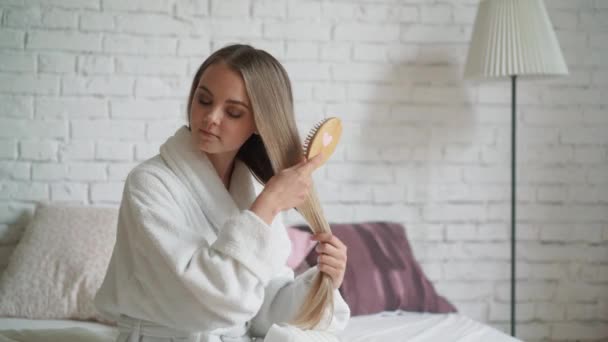 Happy woman in Bathrobe in bedroom combing beautiful long hair. - Кадры, видео