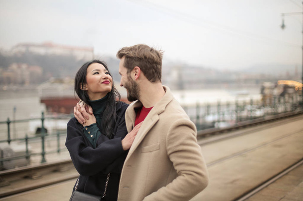 Casal jovem, mulher asiática e um homem europeu se divertindo e andando na cidade no inverno
. - Foto, Imagem