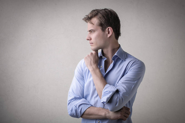Young businessman thinking in a rolled up shirt. - Foto, Imagen