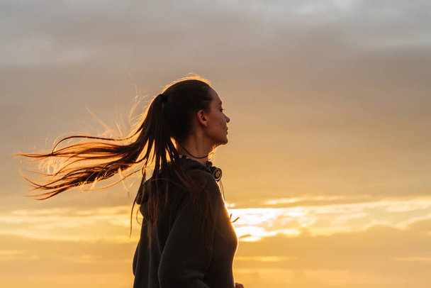 confident strong long-haired girl engaged in jogging at sunset, wants to lose weight - Fotografie, Obrázek