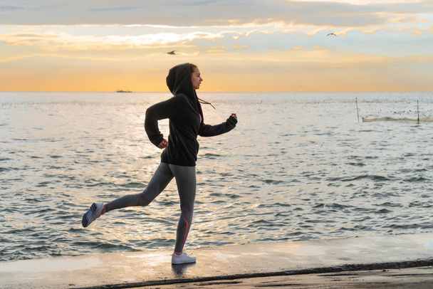 confident active young girl is engaged in jogging at the sea in the evening, wants to lose weight - Fotografie, Obrázek