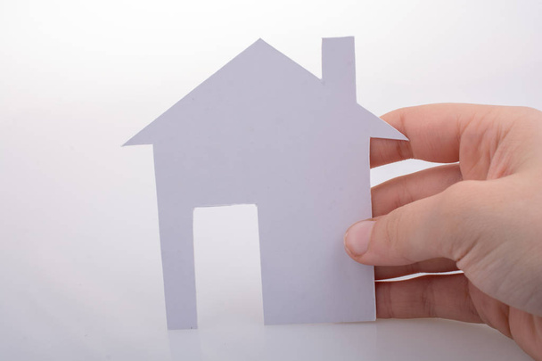 Hand met een papier huis op een witte achtergrond - Foto, afbeelding