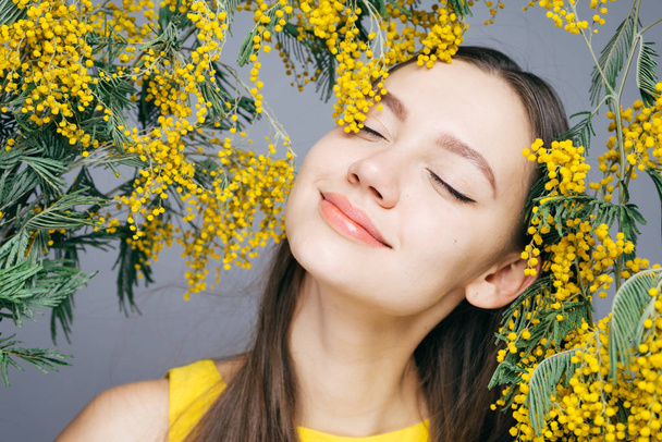 cute smiling girl enjoying the spring and the scent of yellow mimosa - Foto, imagen