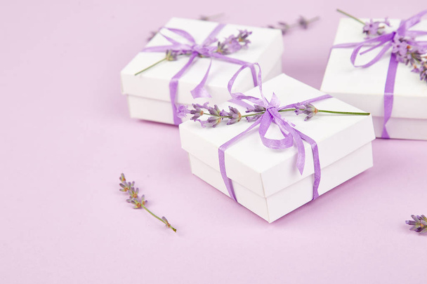 Coffret cadeau blanc avec ruban violet et bouquet de lavande de fleurs sur fond rose. Célébration, anniversaire. Décoration présente. Espace de copie
. - Photo, image