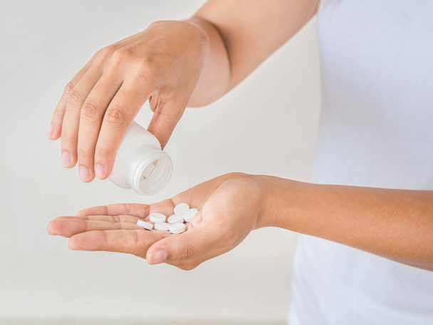 Une jeune femme verse des médicaments, des capsules ou des pilules dans sa main. Soins de santé et concept médical
. - Photo, image