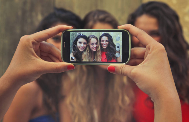 Hands taking photo of a group of girlfriends. - Valokuva, kuva