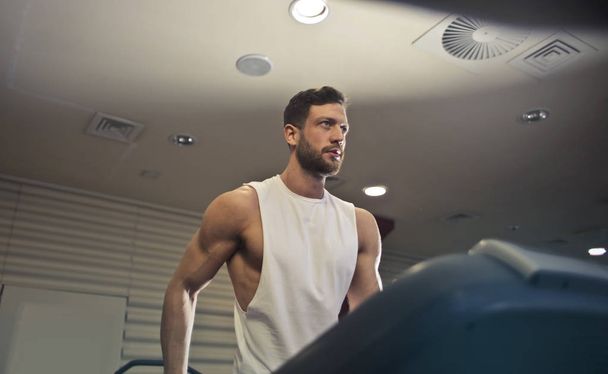 Handsome athletic man doing exercises in the gym. - Foto, afbeelding