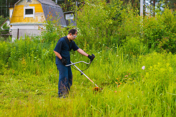 man met een handmatige grasmaaier maait het gras - Foto, afbeelding