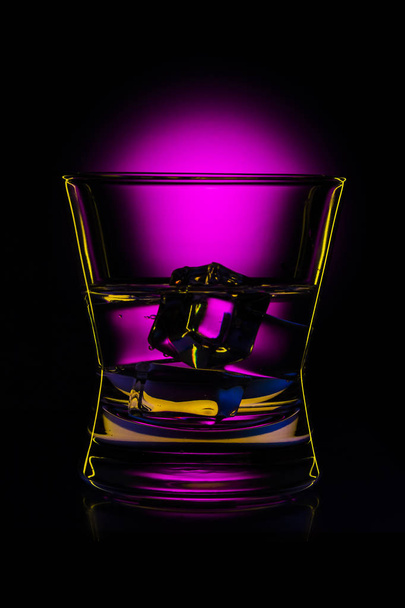 Silhouette beverage glass with drink and ice cubes in bar on black background - Photo, image