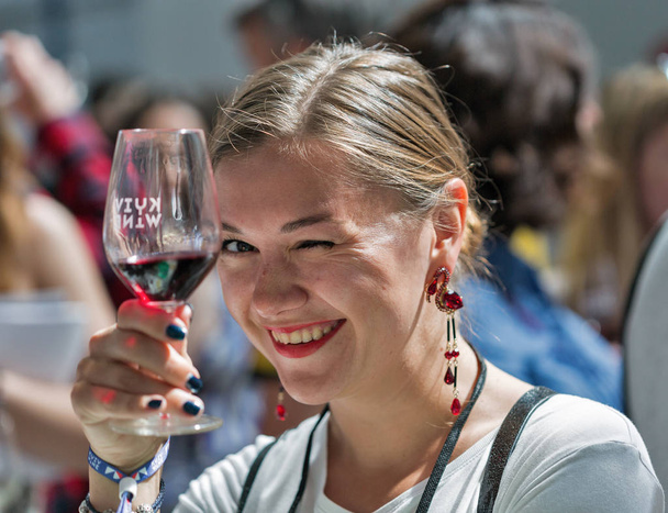 KIEV, UKRAINE - JUNE 2, 2018: Young woman tastes red wine at Kyiv Wine Festival. Big festival of wine and food was organized by Good Wine company, 77 winemakers from around the world took part there. - Valokuva, kuva