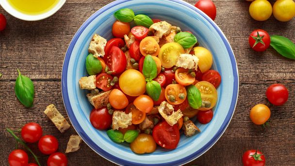 Panzanella Tomato salad with red, yellow, orange cherry tomatoes, capers, basil and ciabatta croutons. summer healthy food. - Photo, Image