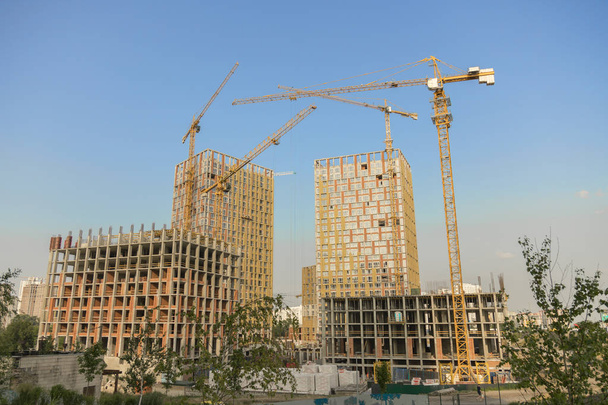 Hoisting crane and new multi-storey building. ndustrial background. Construction of high-rise houses and hoisting tower cranes. New multi-storey housing and large crane. - Photo, Image