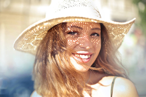 Fiatal gyönyörű nő mosolyogva a nyári nap szalma kalap alatt. - Fotó, kép