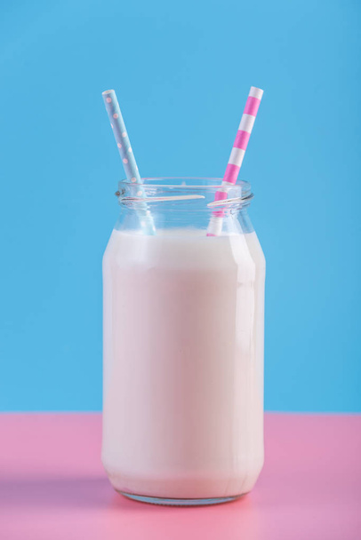 Bottiglia di vetro di latte fresco con due cannucce su fondo pastello. Minimalismo colorato. Il concetto di latticini sani con calcio
 - Foto, immagini