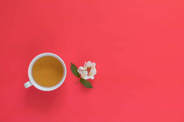 Xícara de chá com branco um buquê de flores de jasmim no fundo vermelho rosa
 - Foto, Imagem