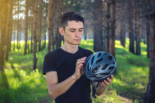 Человек-велосипедист носит спортивный серый шлем на голове на фоне зеленой природы. Концепция обязательной защиты во время велоспорта
 - Фото, изображение