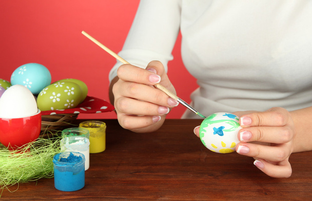 Young woman painting Easter eggs, on color background - Photo, Image